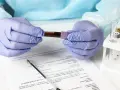 Ręce w rękawiczkach trzymają probówkę z krwią. Wyniki badań wskazują na eozynofile niskie, co może wymagać dalszej diagnostyki.