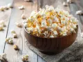 Pyszny popcorn w drewnianej misce, idealny na wieczór filmowy. Zastanawiasz się nad popcorn kcal?