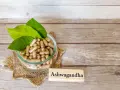 Kapsułki z ashwagandhą w szklanej misce, obok tabliczki z napisem "Ashwagandha". Warto pamiętać o potencjalnych ashwagandha skutki uboczne.