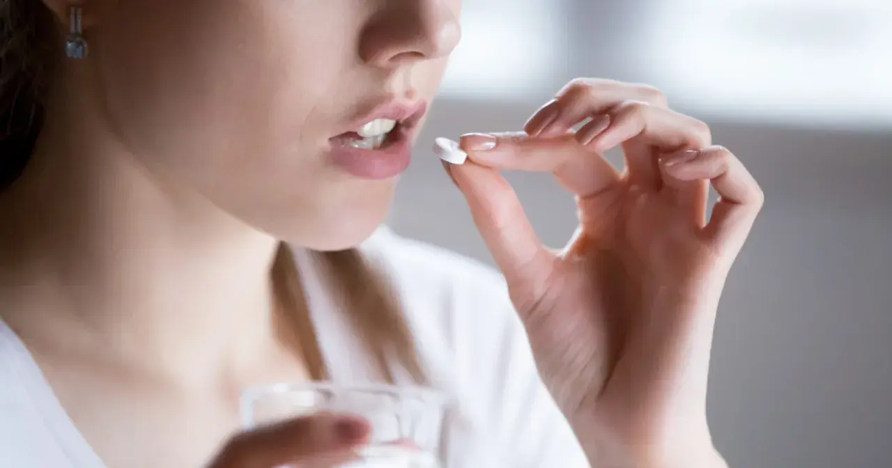 Kobieta bierze tabletkę clindamycin mip 600 na infekcje bakteryjne.