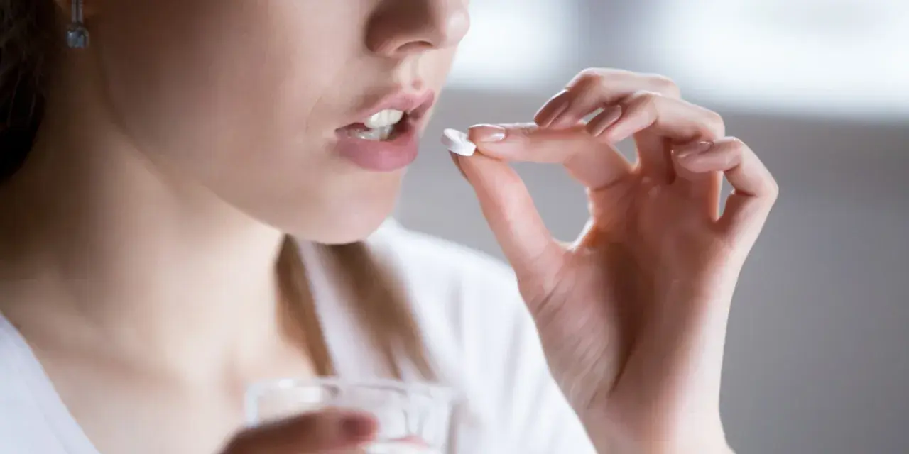 Kobieta bierze tabletkę clindamycin mip 600 na infekcje bakteryjne.