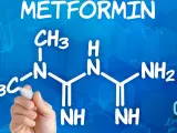 Struktura metforminy i jej potencjalne metformina skutki uboczne. Ręka pisze wzór chemiczny na niebieskim tle.