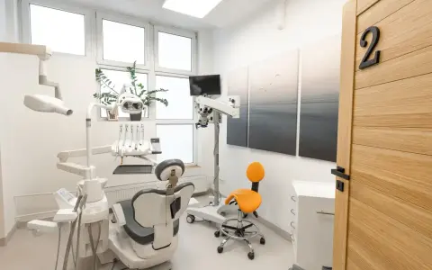 Nowoczesny gabinet stomatologiczny z fotelem, mikroskopem i drzwiami z numerem 2.
