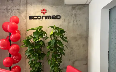 Czerwone balony, logo Scanmed i rośliny w nowoczesnym wnętrzu kliniki medycznej.