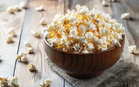 Pyszny popcorn w drewnianej misce, idealny na wieczór filmowy. Zastanawiasz się nad popcorn kcal?