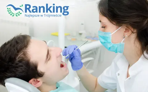 Dentystka w masce bada zęby pacjenta narzędziem stomatologicznym.