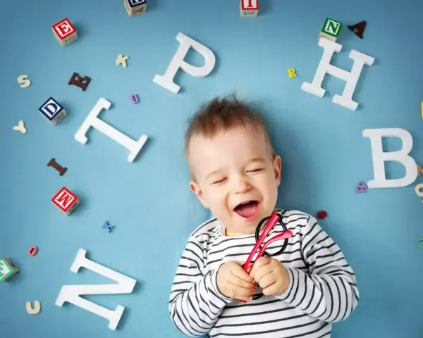Radosny maluch otoczony literkami, jakby właśnie zaczął mówić.