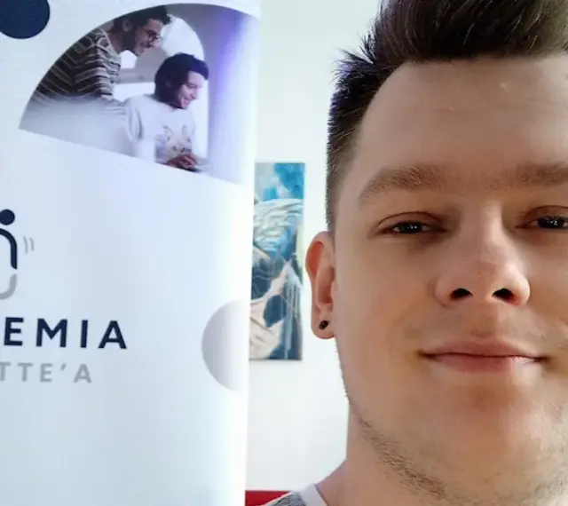 Mężczyzna z tatuażem na uchu obok logo "Akademia Tourette'a".