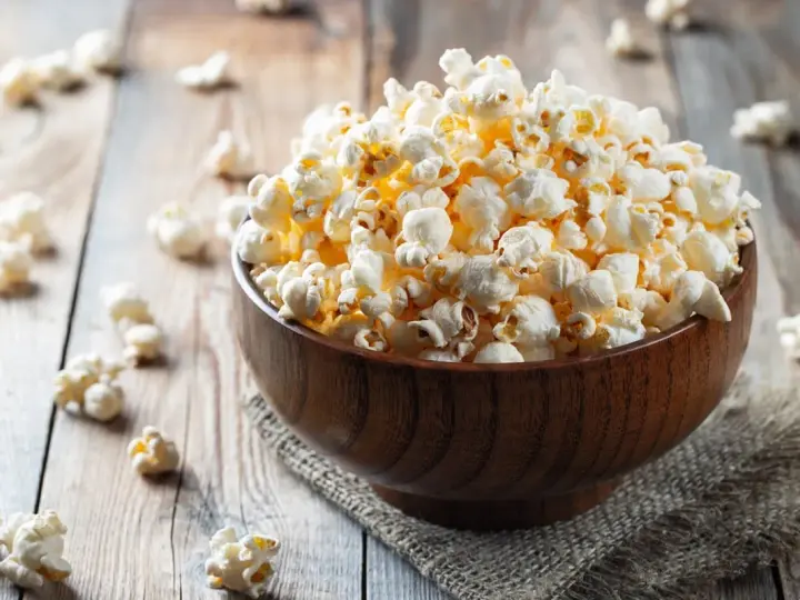 Pyszny popcorn w drewnianej misce, idealny na wieczór filmowy. Zastanawiasz się nad popcorn kcal?