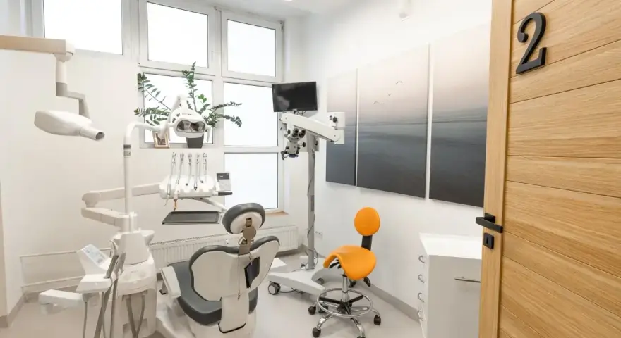 Nowoczesny gabinet stomatologiczny z fotelem, mikroskopem i drzwiami z numerem 2.