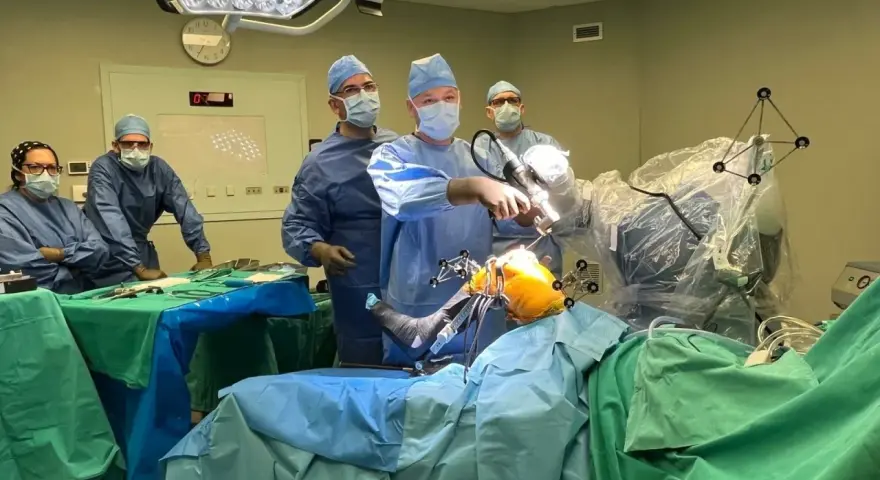 Zespół chirurgów w sali operacyjnej podczas zabiegu ortopedycznego z użyciem robota.