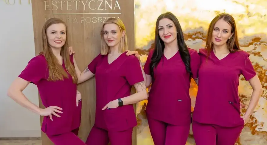 Cztery kobiety w uniformach medycznych stoją obok siebie przed tablicą z napisem "Kosmetologia Estetyczna".