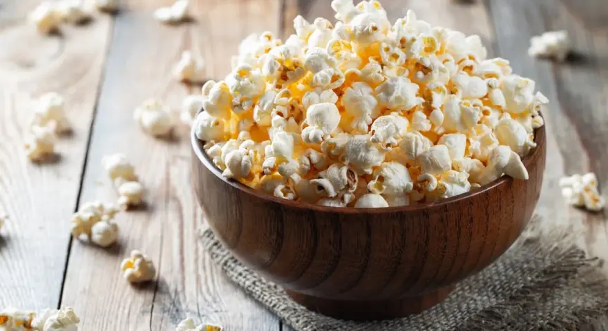 Pyszny popcorn w drewnianej misce, idealny na wieczór filmowy. Zastanawiasz się nad popcorn kcal?