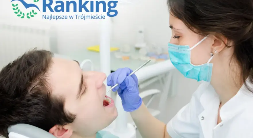 Dentystka w masce bada zęby pacjenta narzędziem stomatologicznym.