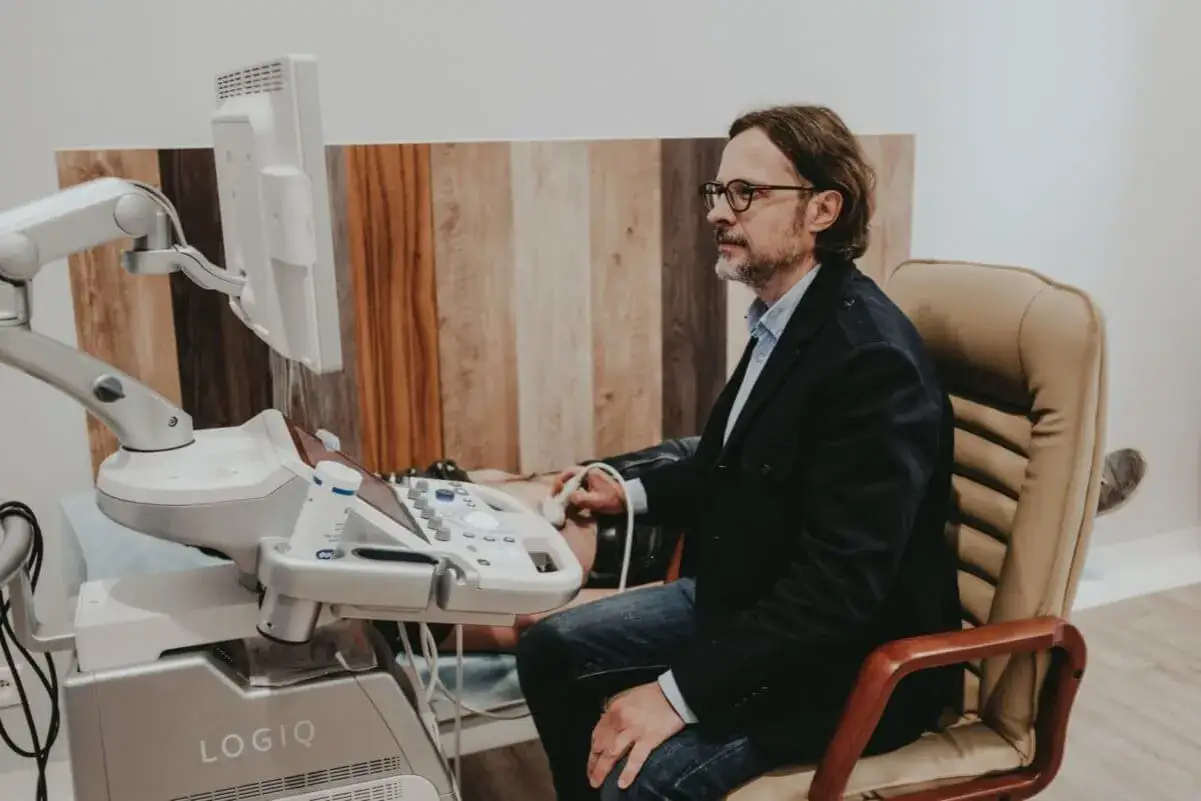 Doświadczony hepatolog wykonuje badanie USG jamy brzusznej, analizując obraz na monitorze aparatu.