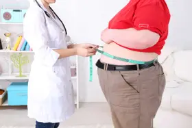 Lekarz obesitolog mierzy obwód talii pacjenta.